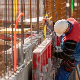 Construction worker in hard hat securing steel reinforcement bars on a job site