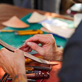 Hands hand stitching leather strap with saddle needles