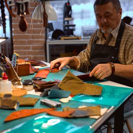 Leather artisan organizing tools and materials at workbench