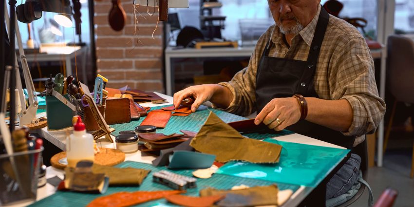 Leather artisan organizing tools and materials at workbench