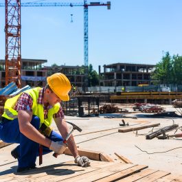 Construction worker hammering wood planks at building site