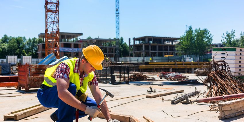 Construction worker hammering wood planks at building site