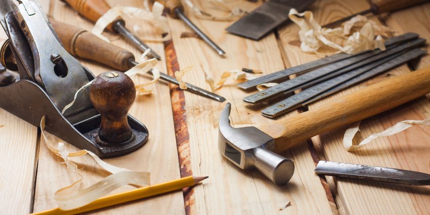 Vintage hand plane, chisels, and hammer on wooden workbench
